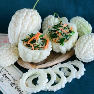 Pearl Goya Bitter Melons stuffed with bitter melon salad on a dark blue background.
