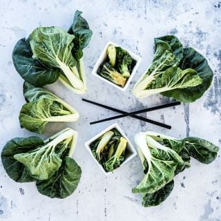 Cooked and fresh Baby Milk Bok Choy on a grey background.