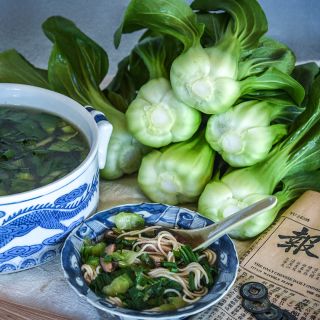 A stack of Suzhou Baby Bok Choy heads with a bowl of soup.