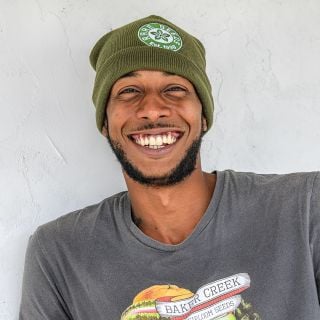 A Baker Creek manager smiles while wearing a Baker Creek Logo Beanie.
