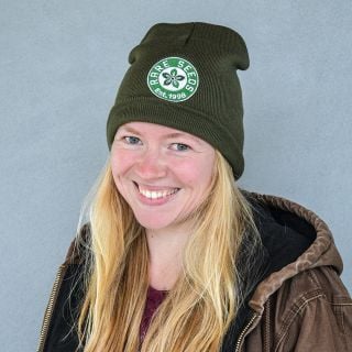 A smiling woman enjoying her Baker Creek Logo Beanie.