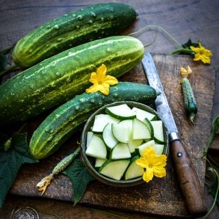 Early Fortune Cucumbers on wooden board with quartered slices.