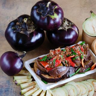 Cut and whole Qi Ye Round Eggplants with an authentic Chinese eggplant recipe on a white plate.