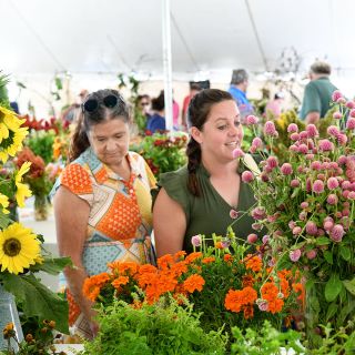 Smiling women admiring flowers at the Baker Creek Fall Harvest Festival.
