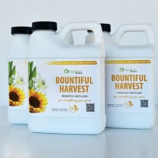 A trio of Bountiful Harvest Prebiotic Fertilizer bottles on a white background.