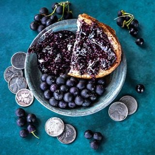 Wonderberry jam with Wonderberries on a teal background with coins.