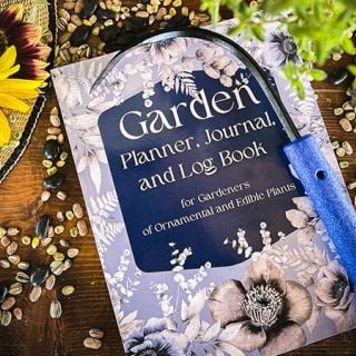 A Gardener's planner booklet with gardening tools and scattered seeds.