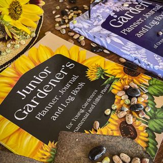 An adult garden planner alongside a Junior Gardener's planner booklet with gardening tools and scattered seeds.