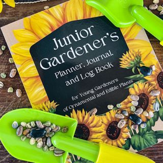 A Junior Gardener's planner booklet with child's gardening tools and scattered seeds.