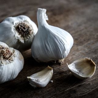 A close-up view of Inchelium Red Garlic bulbs and cloves on wood.