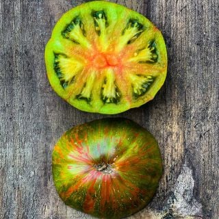 A halved Berkeley Tie-Dye Green Tomato showing both sides on wood. Image by Lucy Hutchins.
