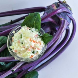 Kohlrabi salad in a glass bowl on top of a bunch of Early Purple Vienna Kohlrabi.