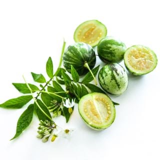 Cut and whole Tzimbalo Melon Pears with flowers and leaves on a light background.