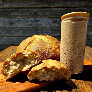 Ms. Debbie’s Rye Starter With loafs of bread on a wood table.