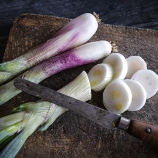 Zebrune Shallot on wooden cutting board with slices.