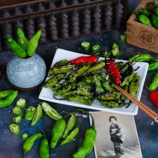 Fresh Shishito Sweet Pepper with grilled peppers on a plate, and Japanese decorations on a dark background. 