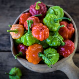 A handmade wooden scoop full of Bonnet Sweet Peppers. 