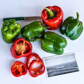 Several California Wonder Sweet Peppers some green and red on a white background.