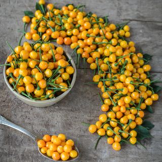 Aji Charapita Peppers on wooden in bowl and filling spoon on wooden table.
