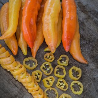 Aji Cristal Peppers, whole and sliced on wooden table top.