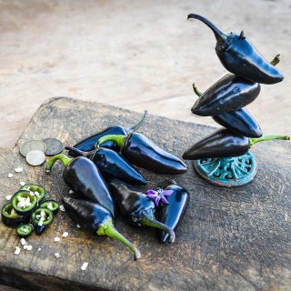 Black Hungarian Peppers with slices on wooden box.
