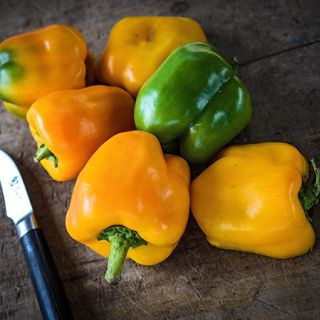 Canary Bell Peppers on a wood cutting board. 