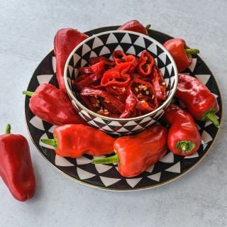 Leutschauer Paprika Peppers on black and white patterned plate and slices in matching, black and white patterned bowl.