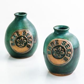 A couple of Handmade Stoneware Pottery Vases with a rareseeds logos on the vases on a white background.
