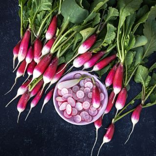 De 18 Jours Radishes with a bolw of cut radishes on a dark black background.