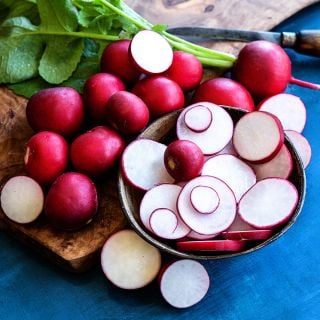 Cut and whole Giant of Sicily Radishes on a blue background.