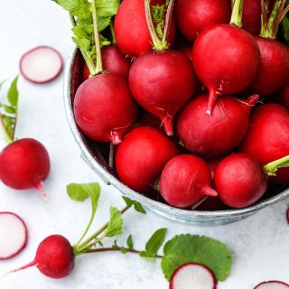 A full colander of Saxa 2 Radishes with slices on a light background.