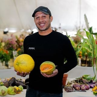A speaker holdig some melons at the Baker Creek Fall Harvest Festival.