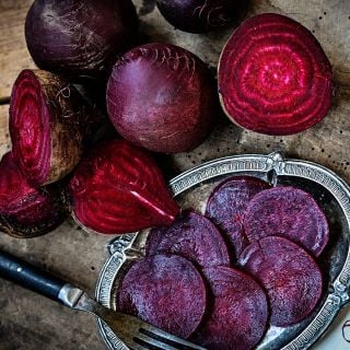 Sliced and whole Betina Beets on a wooden background.