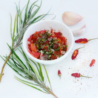 Narrow Leafed Papalo is the garnish on a bowl of salsa surrounded by leaves and peppers.