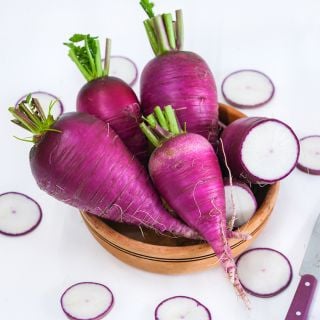 Cut and whole Blue Autumn Radishes surrounded by slices on white background.