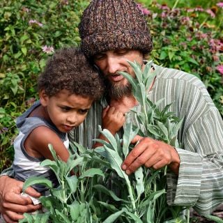 Ryan and his son admiring the Sacred Sage growing in the gardens at Baker Creek.