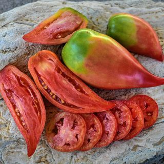 Cut and whole Korean Long Tomatoes on a stone background.