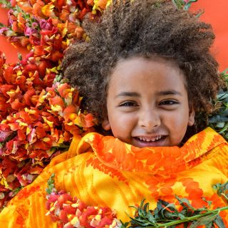 A little boy laughs while he reclines on a bed of Rembrandt Snapdragons.