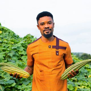 Baker Creek seed grower Solomon Amuzu holding a trio of Krobonko Luffa Gourds in Ghana.