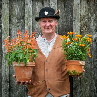 The Bakersville town sheriff holding a couple of blooming plants at the Baker Creek Spring Planting Festival.