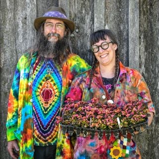A couple shows off their tie-dye outfits with plants at the Baker Creek Spring Planting Festival.