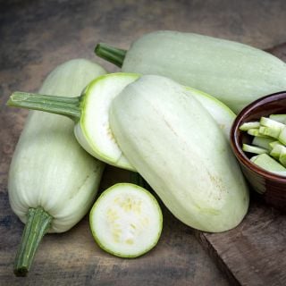 Whole and sliced Odessa Summer Squash arranged on a rustic background.