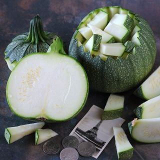 Cut and chopped Ronde De Nice Summer Squash with an image of the Eiffel Tower on dark background.