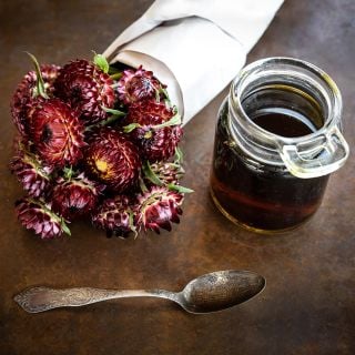 King Size Red Strawflowers with some strawflower tea and spoon on a copper background.