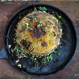 Grilled Mammoth Grey Striped Sunflower head in a cast iron skillet.