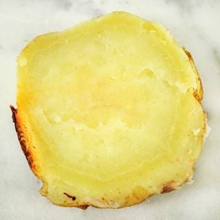 A cooked slice of Jersey Yellow Sweet Potato on white marble.