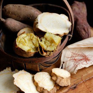 Jersey Yellow sweet potatoes, sliced raw and cooked, in a basket on a wood box.