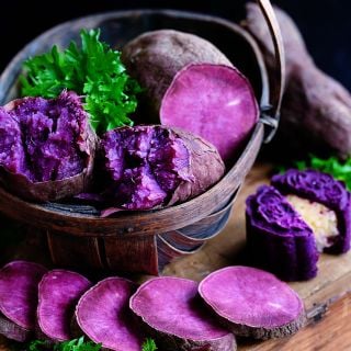 Lilac Beauty Sweet POtatoes in abasket with sweet cakes on a dark background.