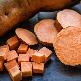 A close-up view of cut and whole Pumpkin Yam Sweet Potatoes.