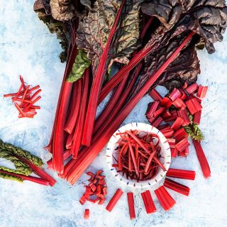 Overhead view of whole and chopped Vulcan Swiss Chard on light blue background.